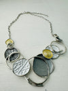 A necklace with a silver and gold color scheme, featuring a series of circular pendants in different shades and a chain displayed on a white background.