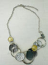 A necklace with a silver and gold color scheme, featuring a series of circular pendants in different shades and a chain displayed on a white background.