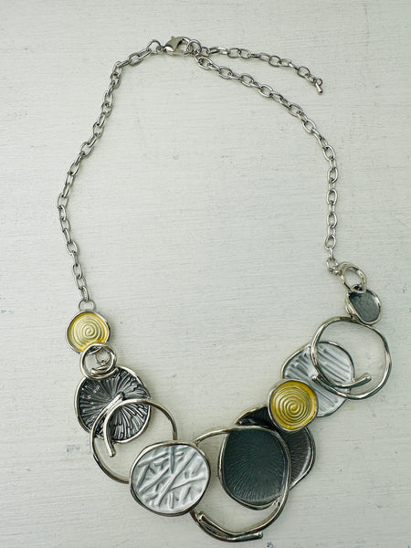 A necklace with a silver and gold color scheme, featuring a series of circular pendants in different shades and a chain displayed on a white background.