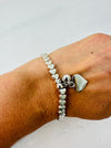 Silver heart-shaped bracelet on a wrist against a light background
