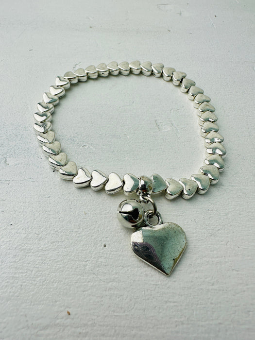 A silver bracelet with a heart-shaped charm, displayed against a white background.