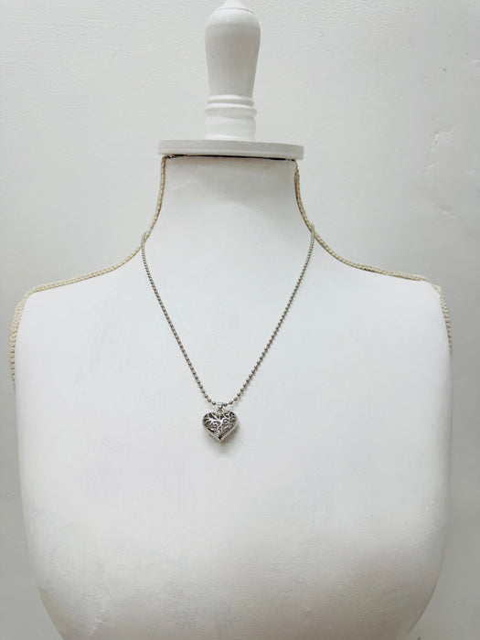 Necklace with a heart-shaped pendant on a mannequin bust against a plain background