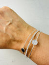 Silver bracelet with a black stone on a wrist against a white background