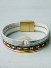 Multi-layered bracelet with gold accents on a light gray background