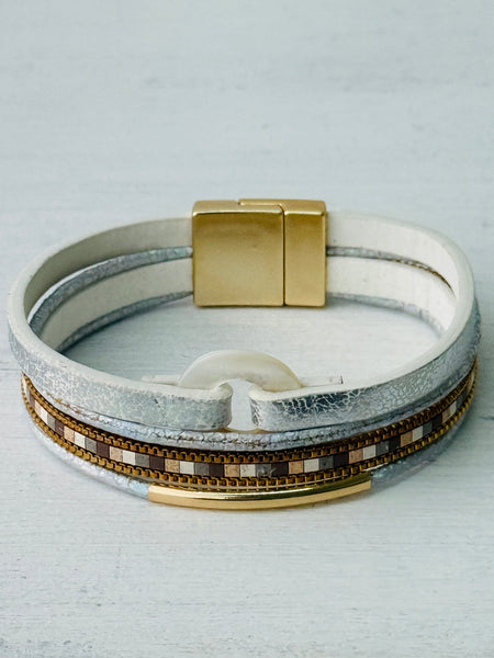 Multi-layered bracelet with gold accents on a light gray background