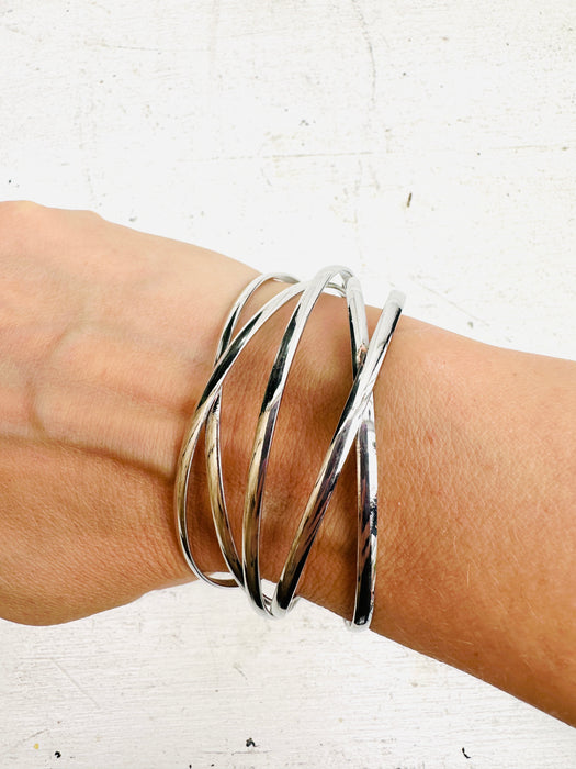 A silver bracelet with a minimalist multi strand cross over design.