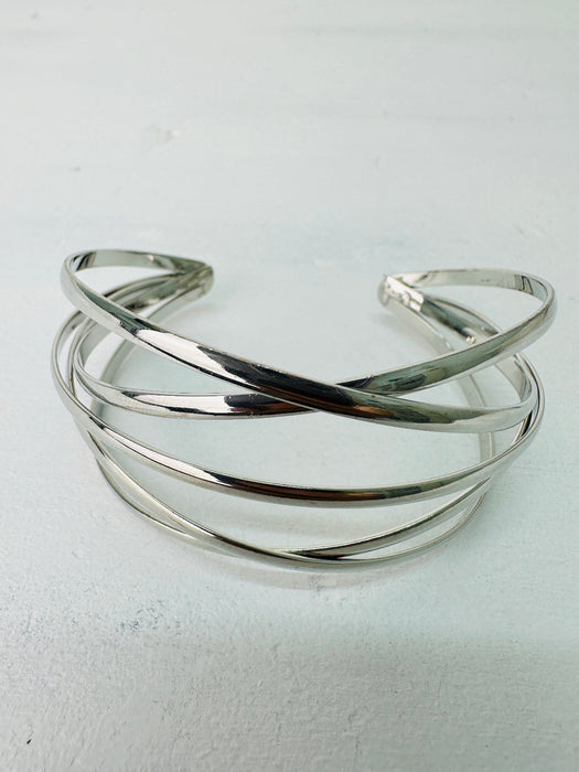 A silver bracelet with a minimalist multi strand cross over design.