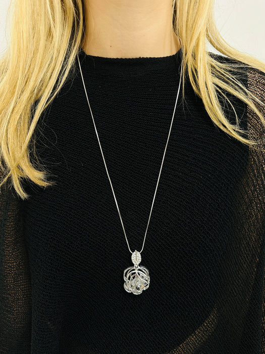 Silver necklace with a pendant worn by a person in a black top