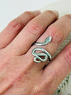 Silver snake-shaped ring on a person's finger against a white background