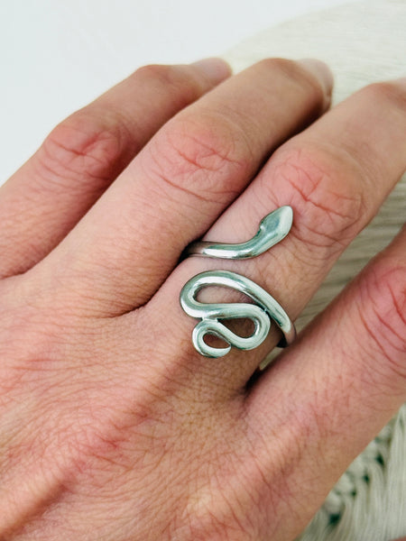 Silver snake-shaped ring on a person's finger against a white background