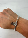 Silver bracelet with star charms on a wrist against a light background