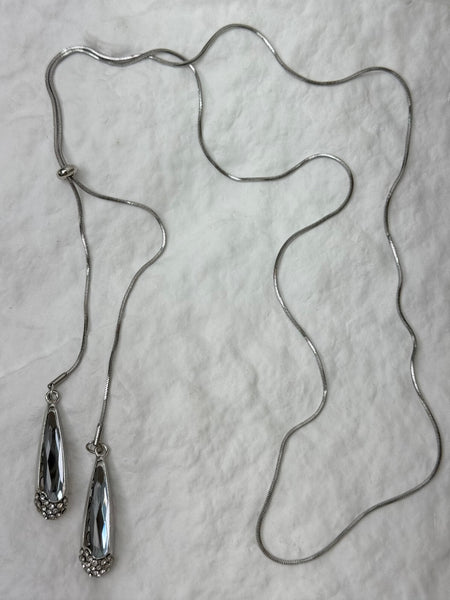 Silver necklace with two pendant ends on a light gray background