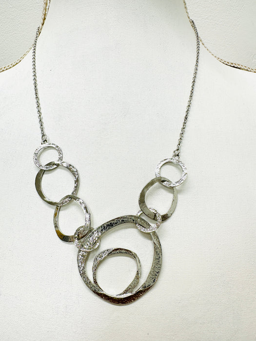  close-up of silver textured circle link necklace with abstract overlapping rings