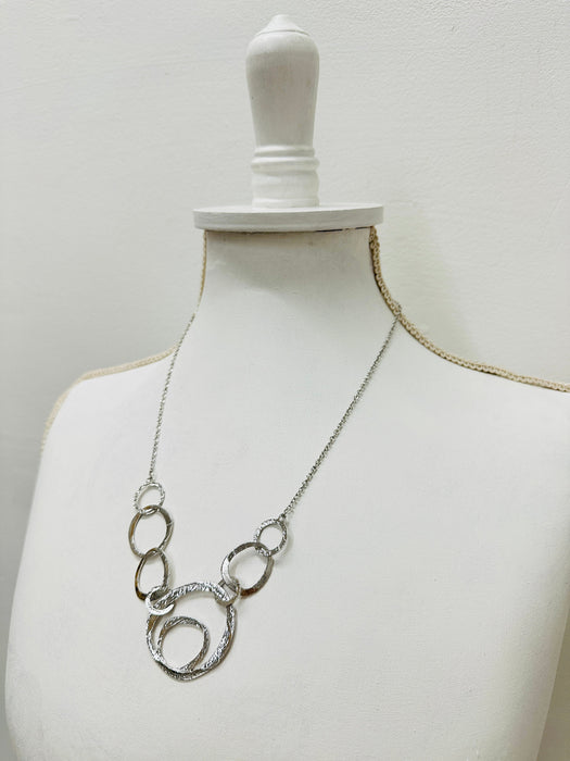 side angle of silver textured circle link necklace with abstract overlapping rings