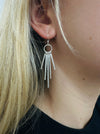 Silver fringe earring worn by a person with blonde hair.