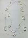 A silver necklace with multiple geometric pendants laid out on a flat surface.