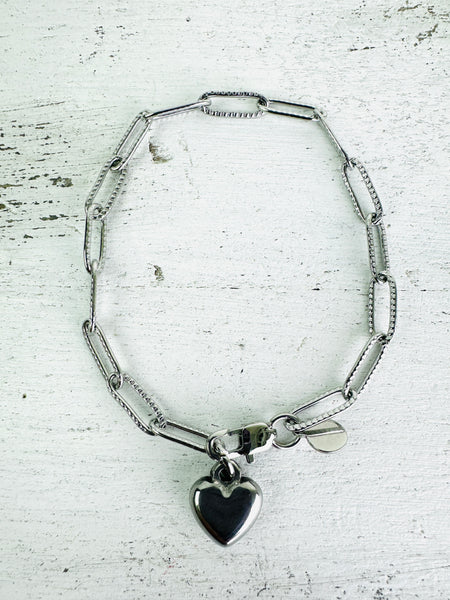 Silver-tone link chain bracelet with polished heart charm, displayed on a white background.