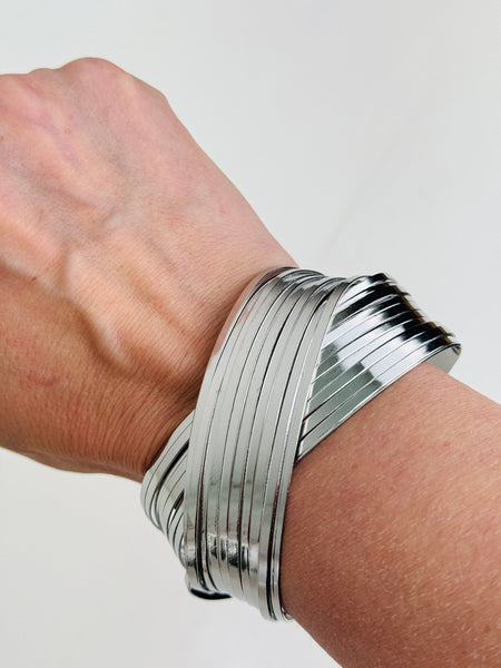 Silver layered cuff bracelet with overlapping metal bands and polished finish dispayed on a model