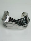 Silver layered cuff bracelet with overlapping metal bands and polished finish displayed on a white background