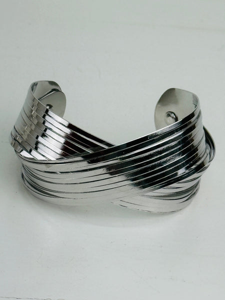 Silver layered cuff bracelet with overlapping metal bands and polished finish displayed on a white background