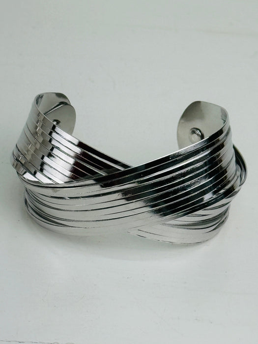 Silver layered cuff bracelet with overlapping metal bands and polished finish displayed on a white background