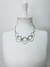 modern silver tone necklace with layered open circles displayed on a mannequin