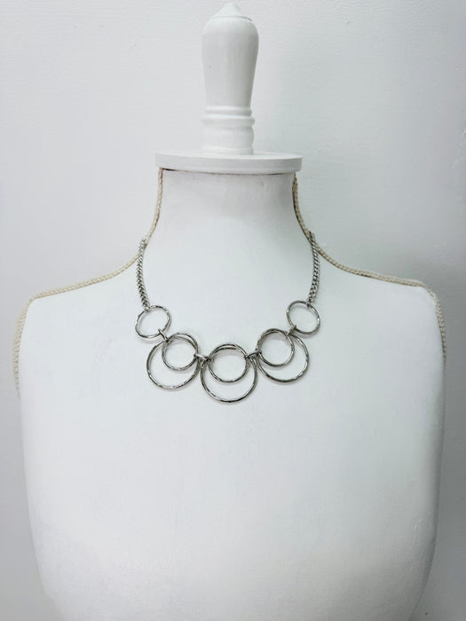 modern silver tone necklace with layered open circles displayed on a mannequin