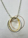 close-up of silver chain necklace with three interlinked mixed metal rings in gold, rose gold, and silver colours