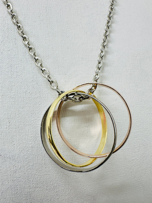 close-up of silver chain necklace with three interlinked mixed metal rings in gold, rose gold, and silver colours