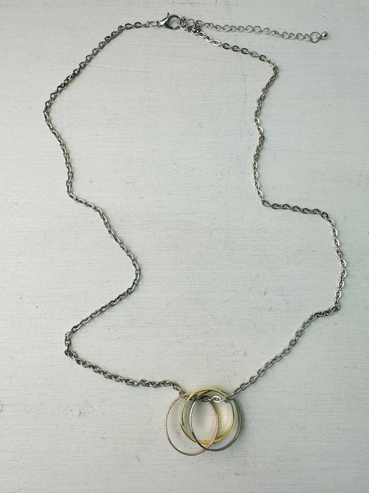 Silver chain necklace with three interlinked mixed metal rings in gold, rose gold, and silver colours