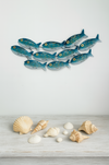 Small aqua striped metal fish shoal wall art displayed above coastal-style décor with shells