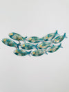Angled view of small aqua metal fish shoal wall décor arranged in a curved formation