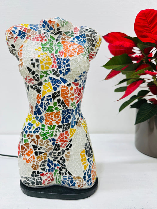 Decorative mosaic bust lamp displayed beside red poinsettia plant.