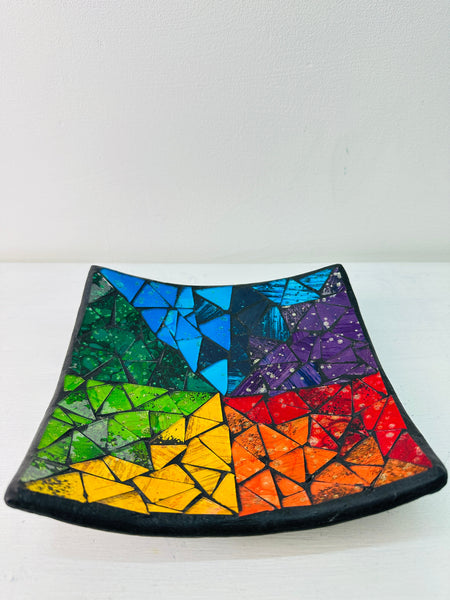 Front view of handmade rainbow mosaic glass plate showing vivid red, yellow, blue, and green tones against white background.