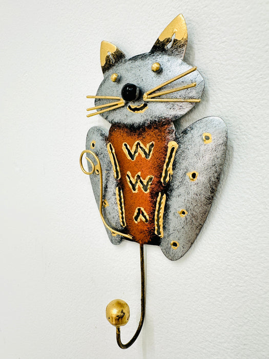 Handmade and hand painted smiley cat hook in copper and silver with gold detailing, mounted on a wall.