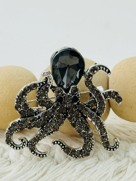 Silver octopus brooch with a smoke grey crystals on a white background