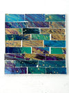 Square Cyan Brick mosaic coaster with hand-painted glass rectangles in blue and green tones arranged on an MDF base, photographed from above on a light surface.
