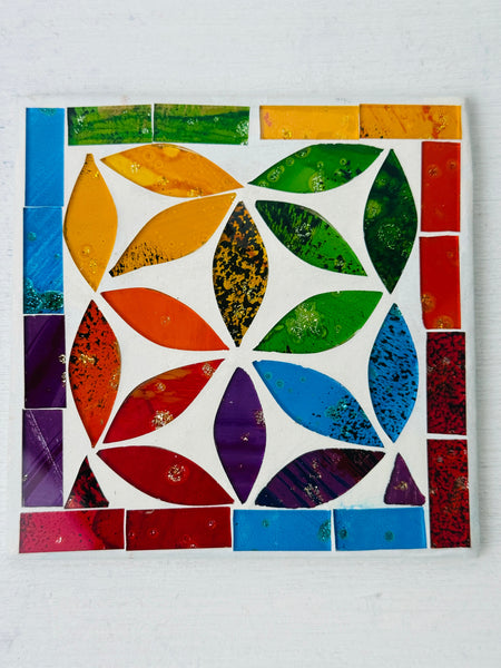 Square Peacock mosaic coaster with colourful hand-painted glass pieces arranged in a geometric feather-inspired pattern on MDF base, photographed from above on a light surface.