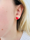 Red strawberry-shaped earrings with gold tops on a model