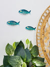 Aqua striped metal fish wall art displayed beside indoor plants and decorative plate