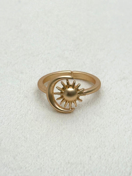 Gold ring with sun and moon design on a white background