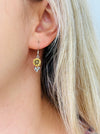 Close-up of a sunflower dangle earring, displayed on a model. 