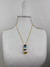 Gold necklace with a detailed pendant on a mannequin bust against a gray background