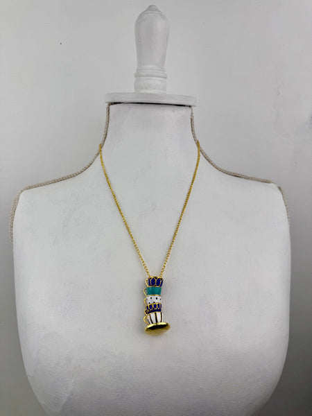 Gold necklace with a detailed pendant on a mannequin bust against a gray background