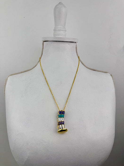 Gold necklace with a detailed pendant on a mannequin bust against a gray background