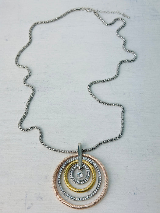 A necklace with three concentric circles in silver, rose gold, and gold colors, featuring a Lobster clasp fastening on a chain.