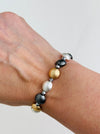 Tri-tone metallic beaded elastic bracelet in gold, silver and dark grey tones with grey spacer beads, displayed on a model.