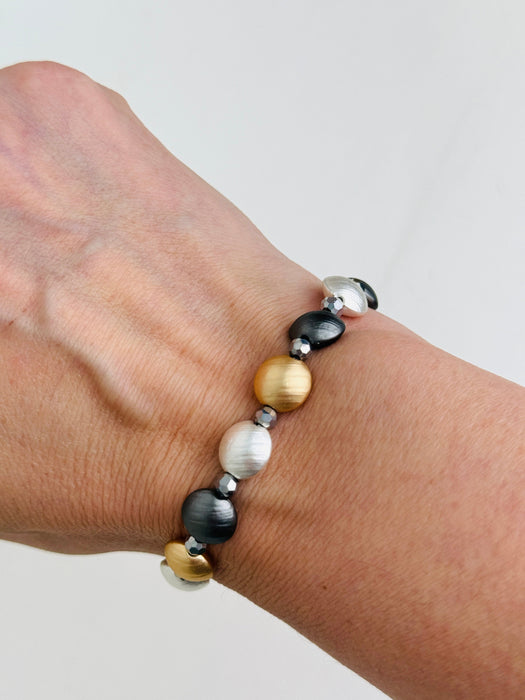Tri-tone metallic beaded elastic bracelet in gold, silver and dark grey tones with grey spacer beads, displayed on a model.
