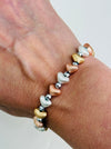 Tri-tone metallic beaded elastic bracelet in gold, silver and rose gold tones with grey spacer beads, displayed on a model.
