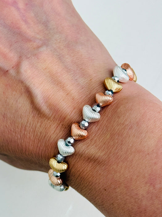 Tri-tone metallic beaded elastic bracelet in gold, silver and rose gold tones with grey spacer beads, displayed on a model.